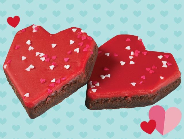 Two heart shaped brownies with red frosting and sprinkles