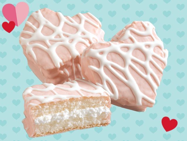 Heart shaped cookies with white frosting on a pink background