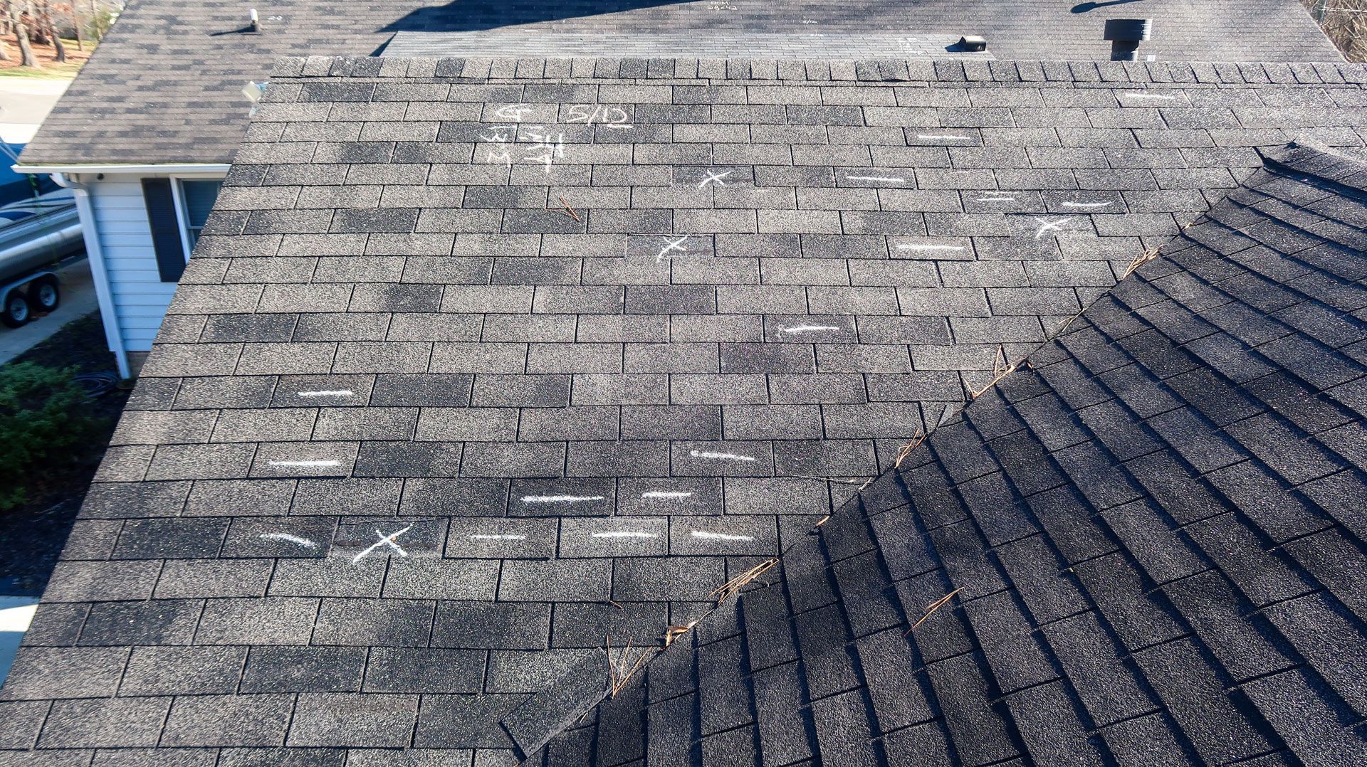 Two construction workers are working on a tiled roof.