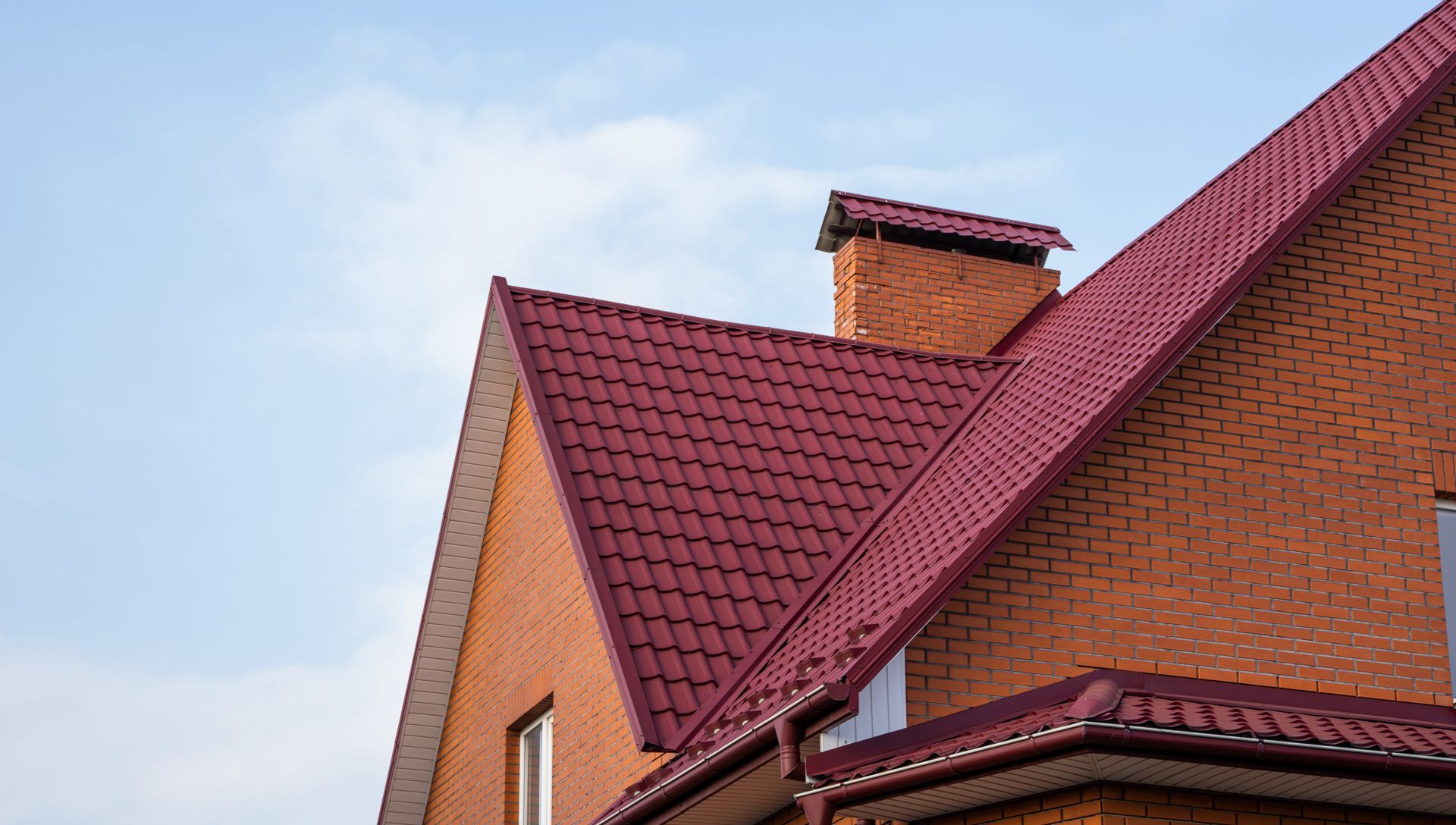 A brick house with a red roof and a chimney.
