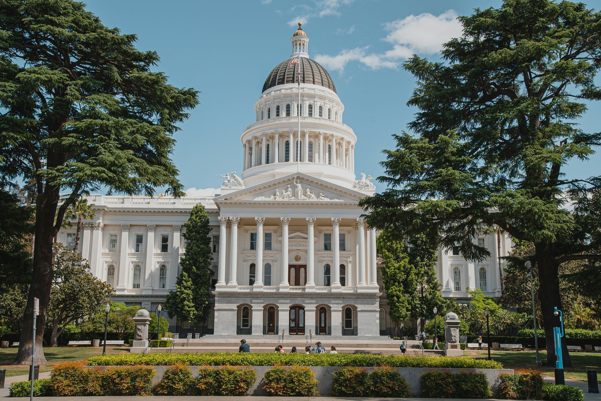 California State Capitol building with dome, trees, and blue sky.