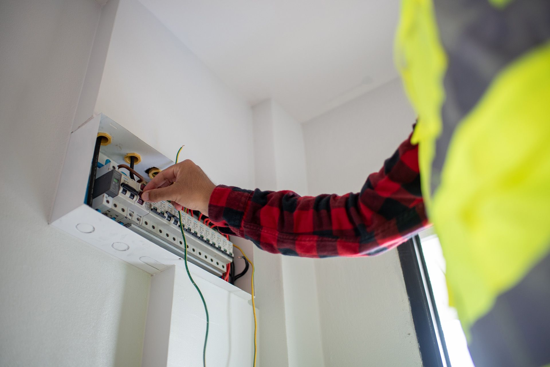 An electrician is working on wiring the electrical system in a house. An electrician is working on wiring the electrical system in a house.