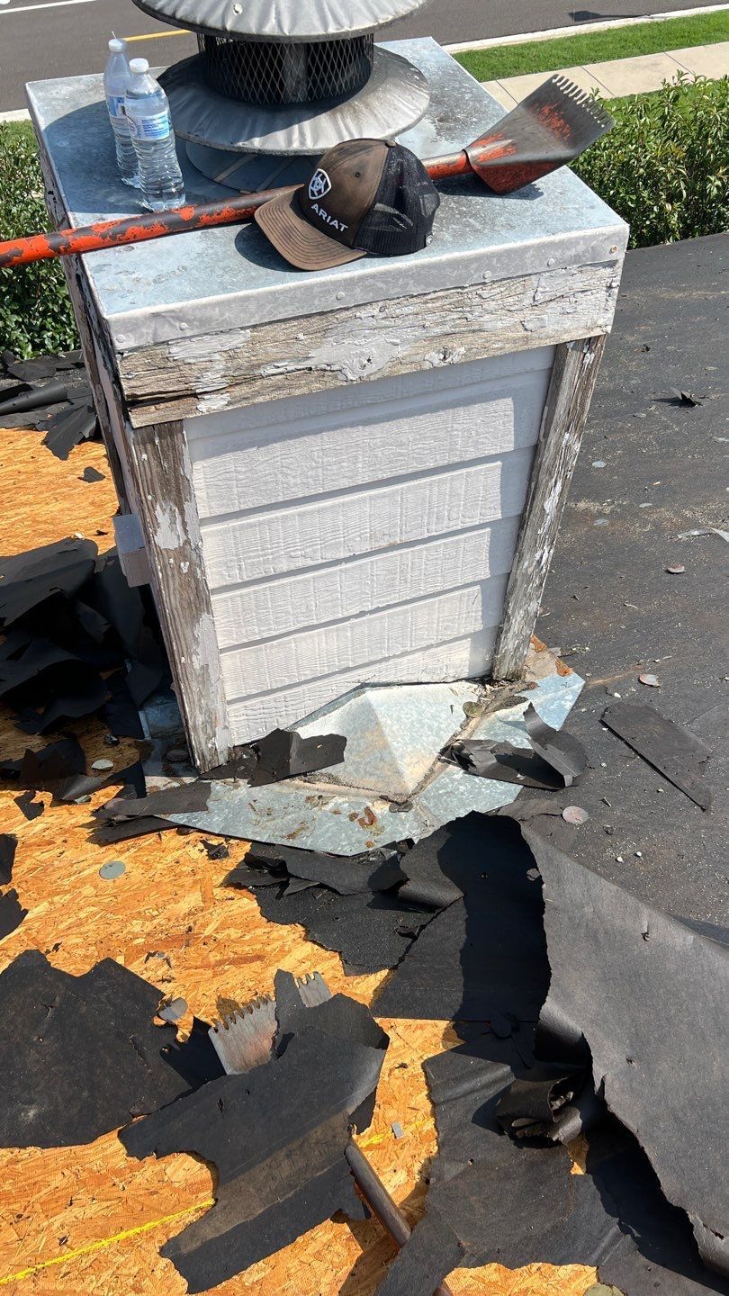 A chimney is sitting on top of a roof next to a hat and a shovel.