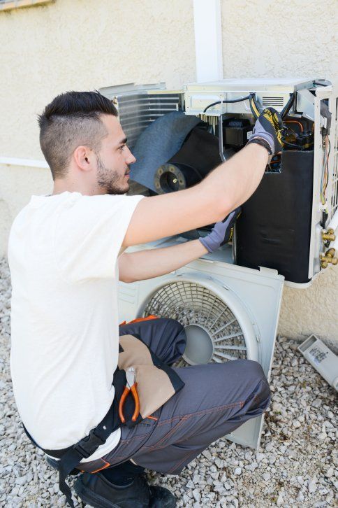 Man electrician installing air conditioning - Plumbing and Heating Service in Bloomington, IL
