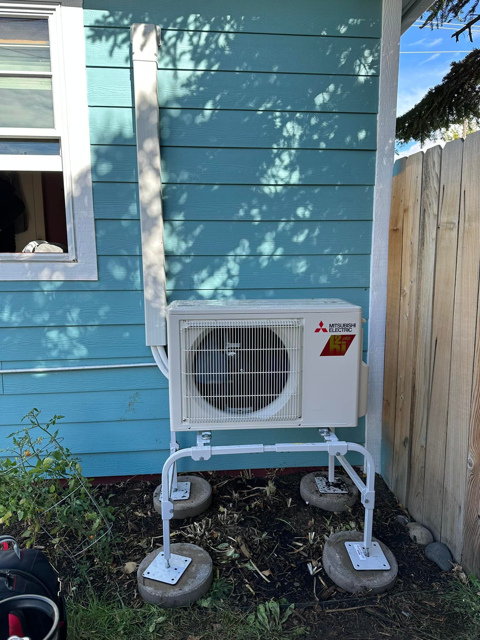A blue house with a white air conditioner on the side of it.