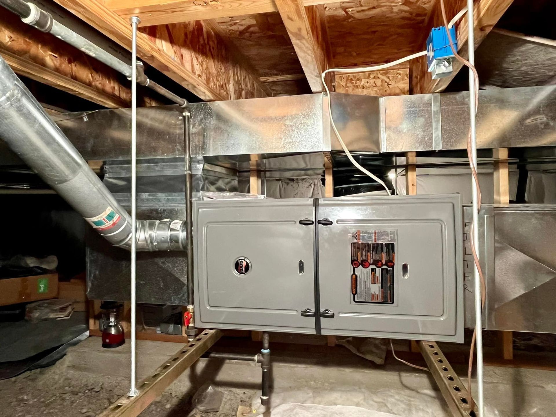 A electrical box is hanging from the ceiling of a basement.