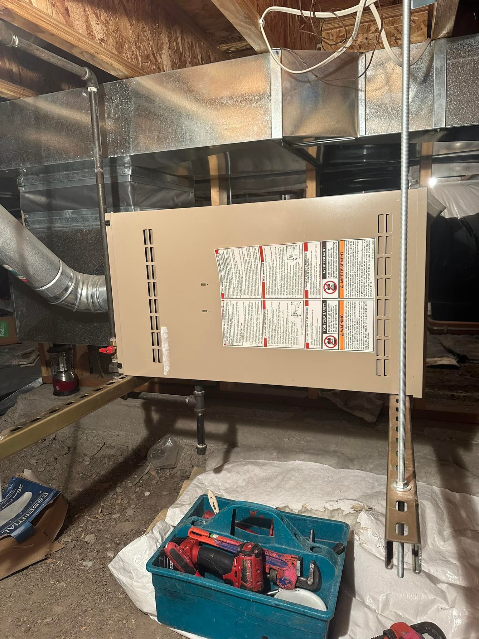 A box of tools is sitting next to a furnace in a basement.