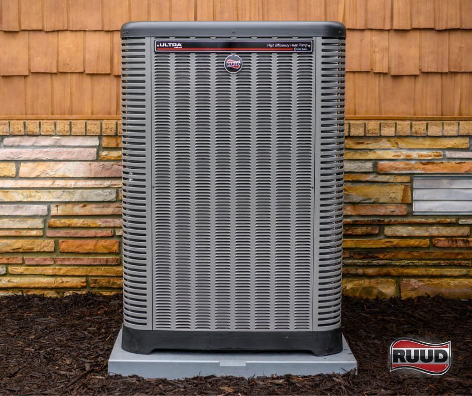 A ruud air conditioner is sitting in front of a brick wall