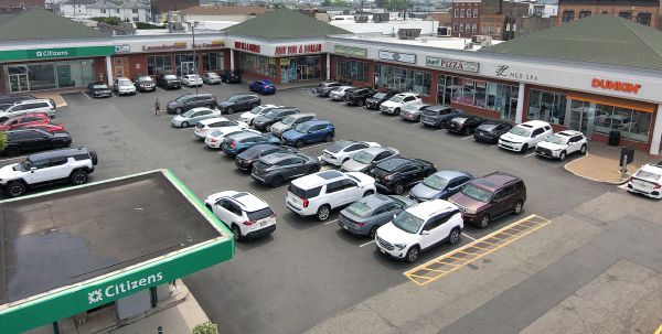 Aerial view of a shopping plaza with parked cars and storefronts. Includes a Citizens Bank and a Dunkin'.