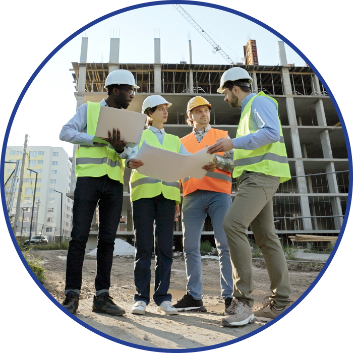 Construction workers in safety vests and hard hats reviewing blueprints on a construction site.