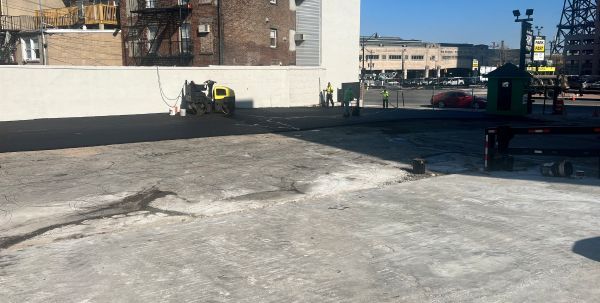 Workers on a construction site, pouring concrete. Sunlight on a flat surface next to a building in the city.