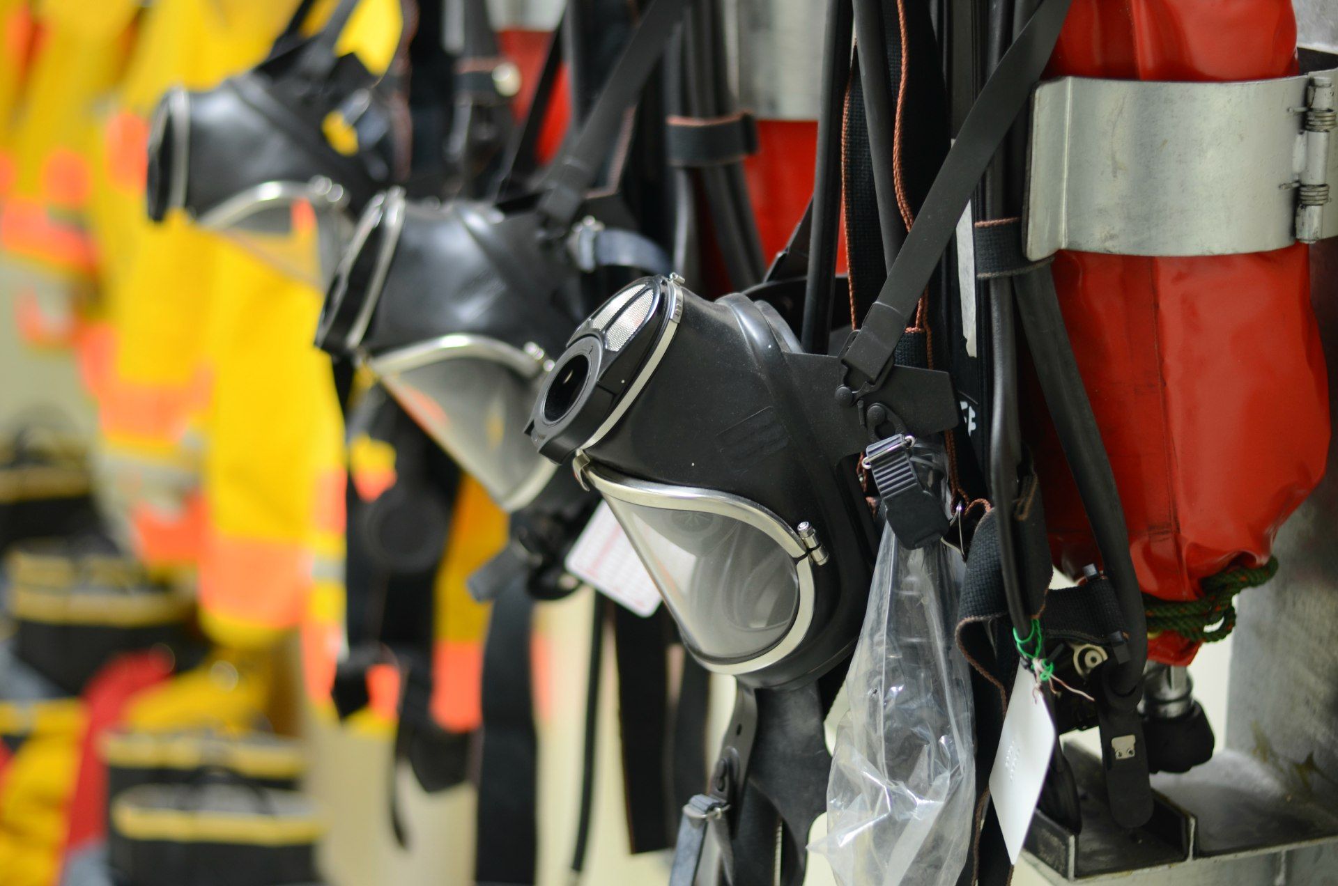 Firefighter masks and air tanks hanging on a wall.