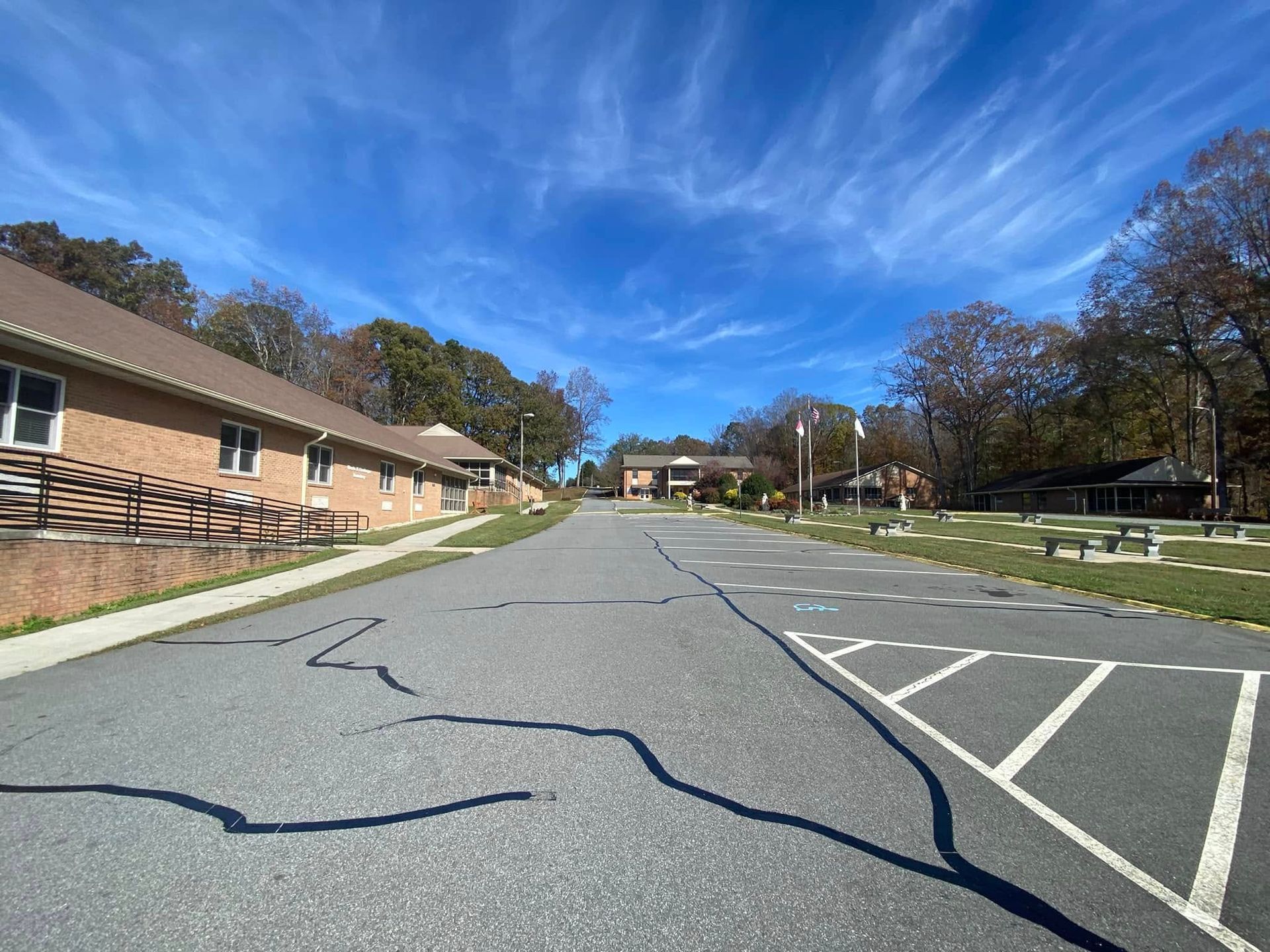 Empty parking lot beside a brick building under a bright blue sky.