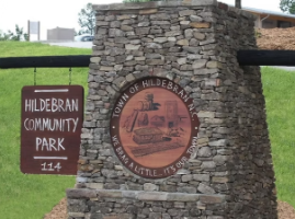 Hildebran Community Park sign beside a stone pillar with town seal plaque