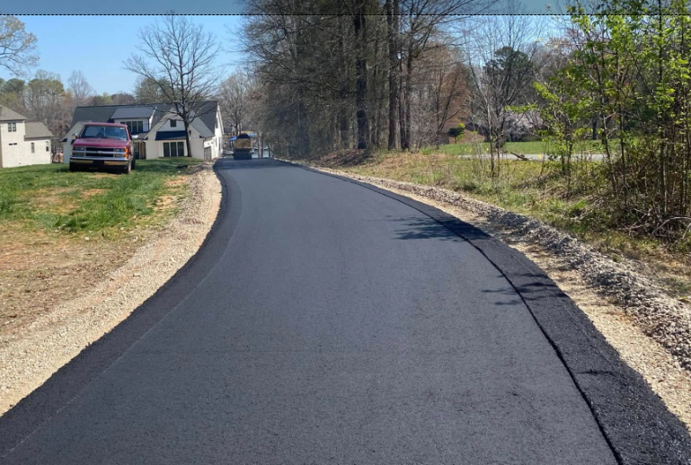 Freshly paved curving road in a suburban neighborhood with houses and trees alongside it