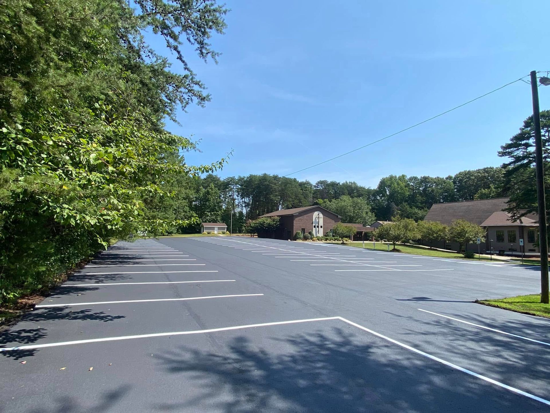 Empty parking lot beside trees and brick buildings on a sunny day