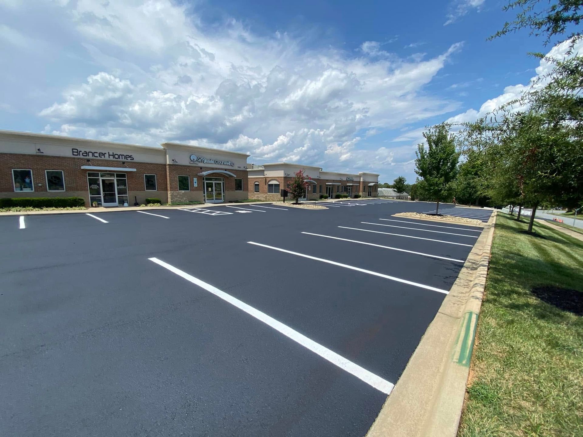 Empty parking lot in front of a brick shopping center under a blue sky