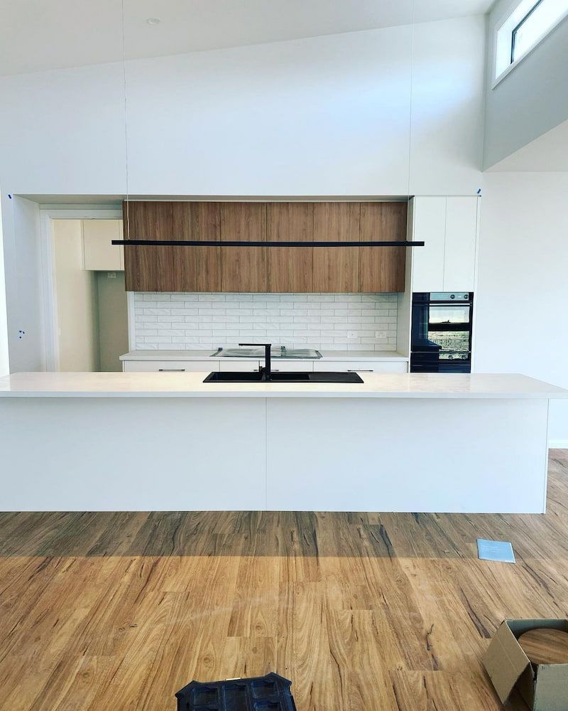 A Kitchen With White Cabinets And A Wooden Floor — AdvancedOne Electrical in Alfredton, VIC