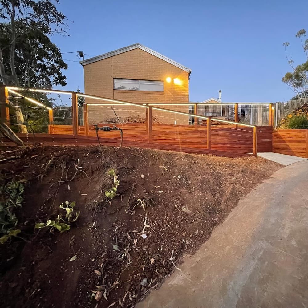 A House Is Behind A Wooden Fence With Lights On It — AdvancedOne Electrical in Alfredton, VIC