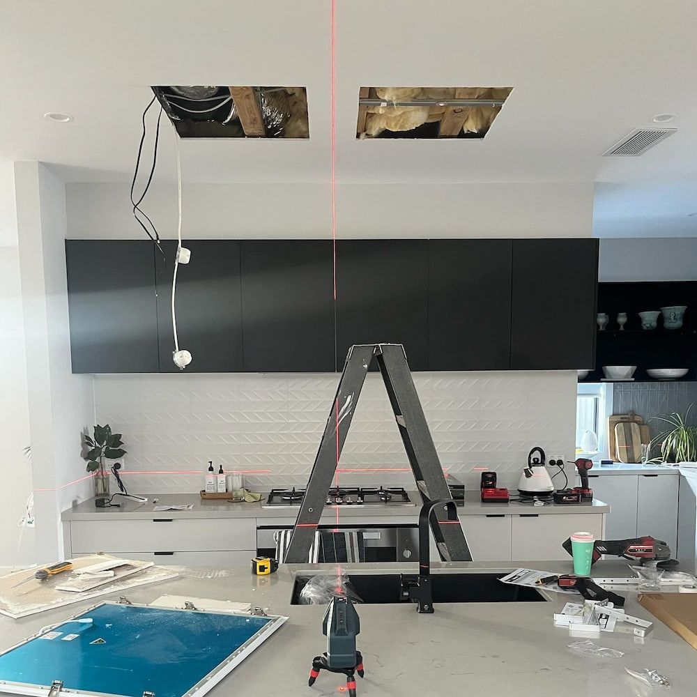 A Kitchen With Black Cabinets And A Ladder On The Counter — AdvancedOne Electrical in Alfredton, VIC