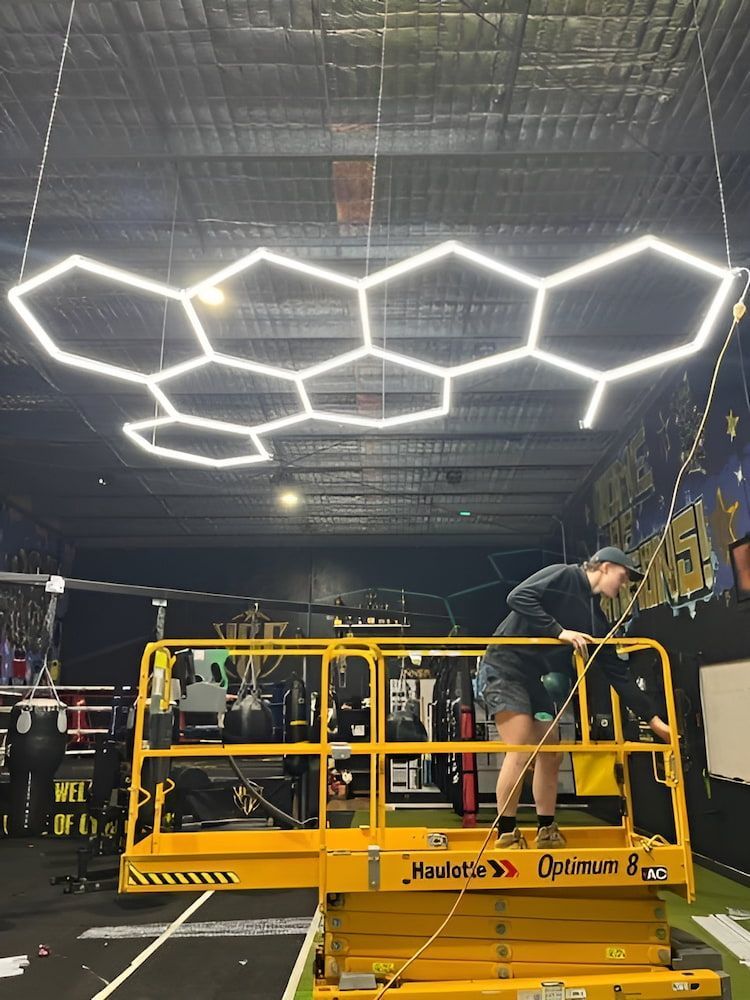 A Man Is Standing On A Lift Working On A Ceiling Light — AdvancedOne Electrical in Alfredton, VIC
