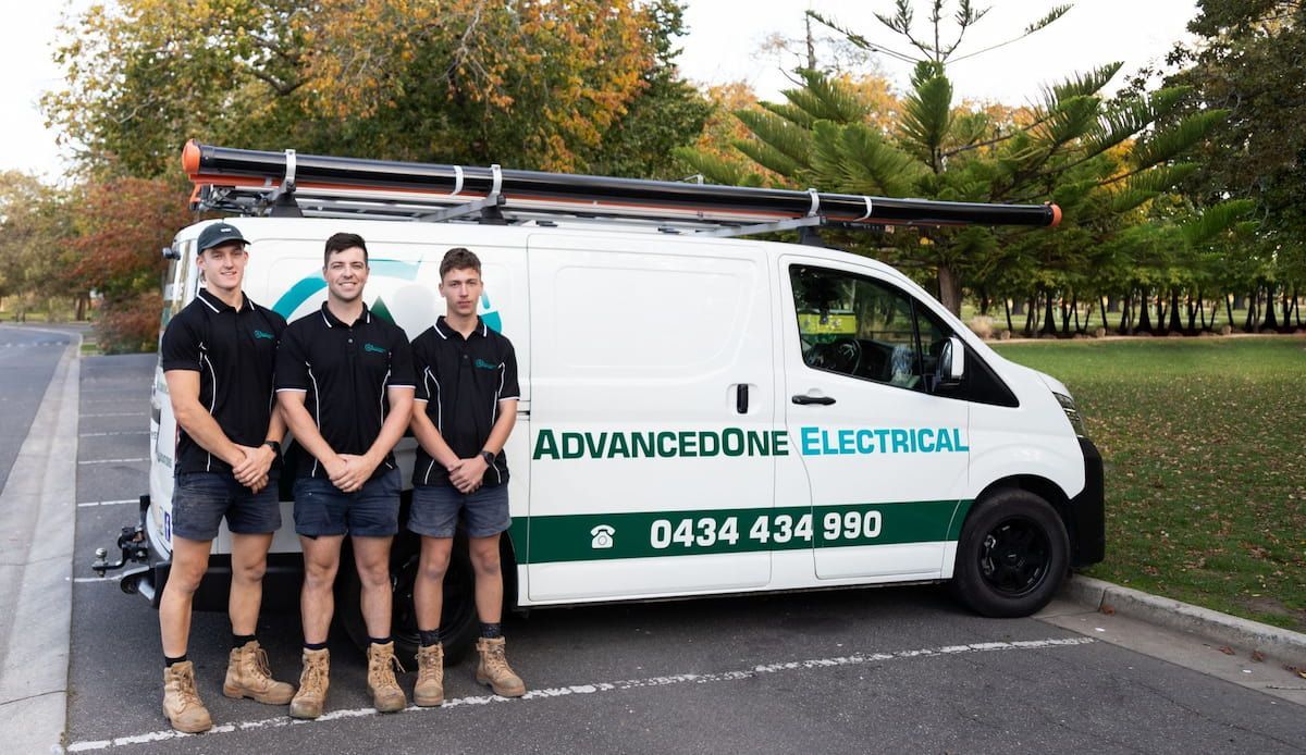 A Group Of Men Are Standing In Front Of An Advanced One Electrical Van — AdvancedOne Electrical in Alfredton, VIC