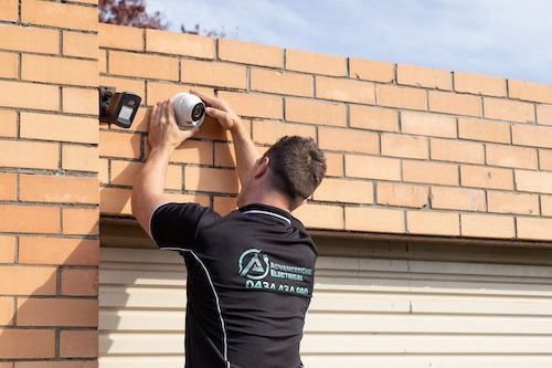 A Man Wearing A Hard Hat And Mask Is Working On A Fire Alarm System — AdvancedOne Electrical in Alfredton, VIC