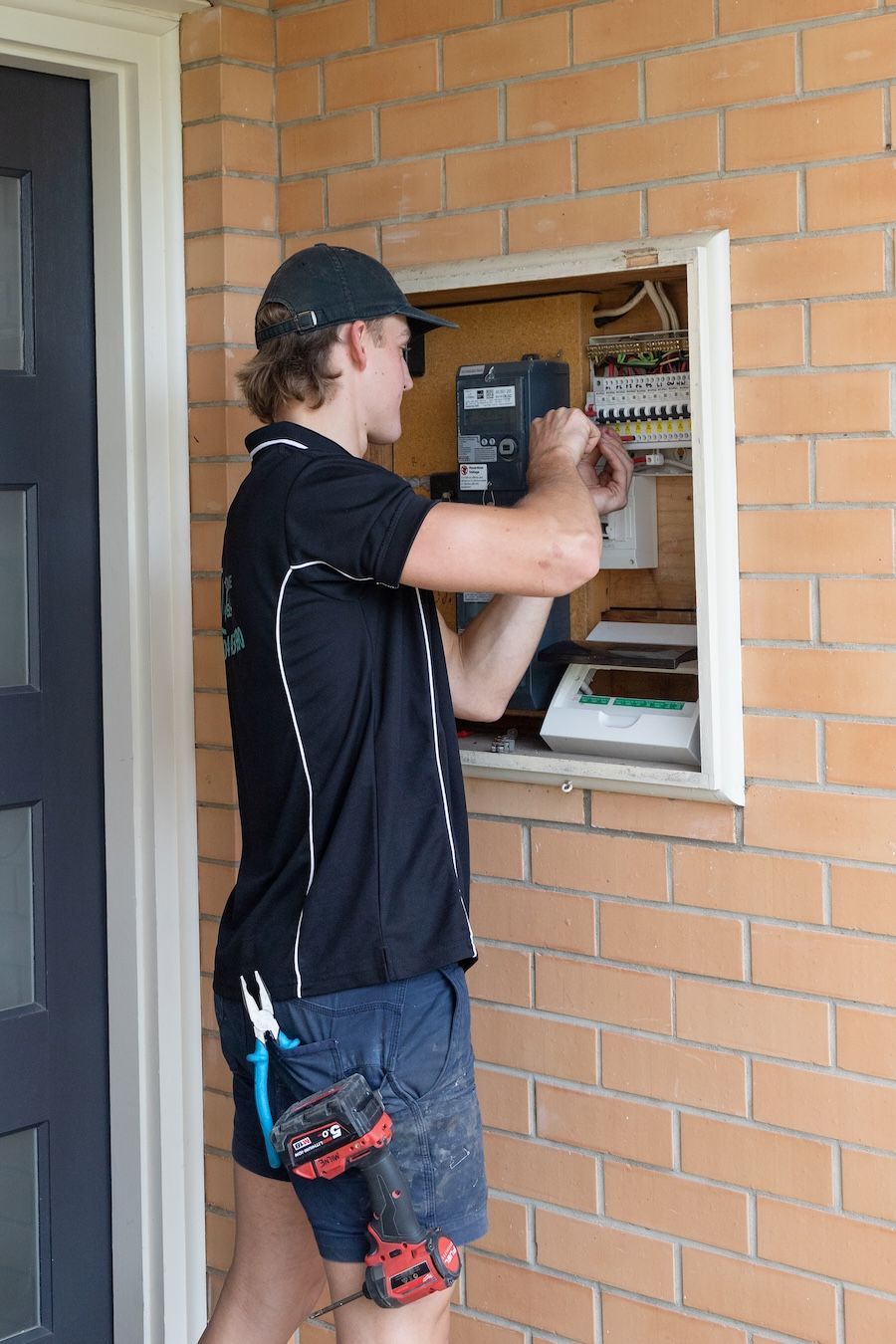 A Man In A Hat Is Standing In Front Of An Electrical Box — AdvancedOne Electrical in Alfredton, VIC