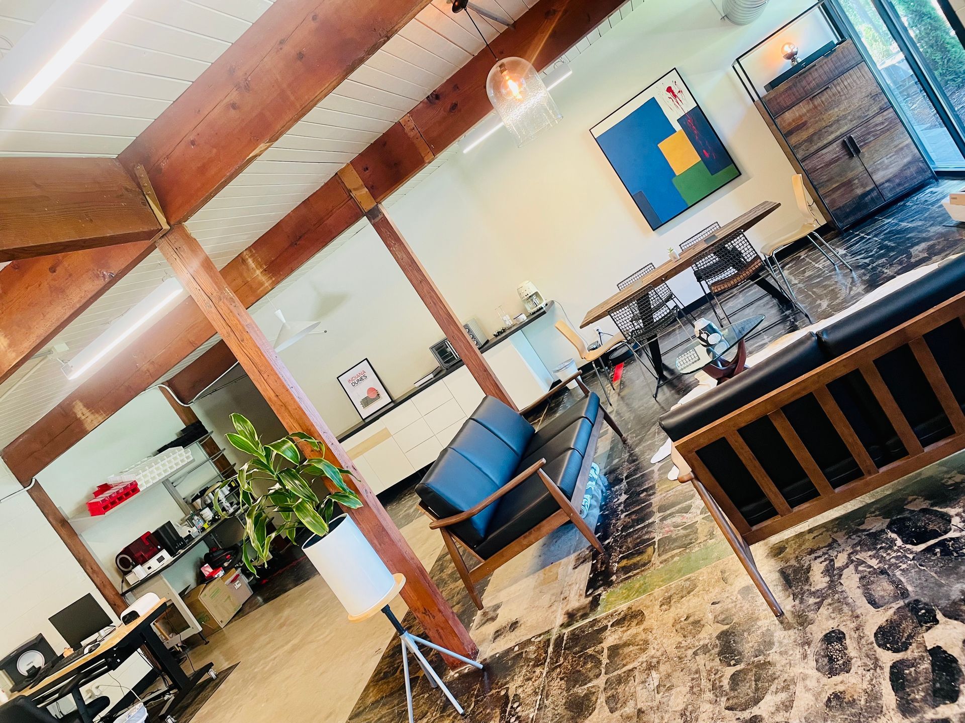 Interior view of a modern office space, with wood beams, blue seating, and abstract art.