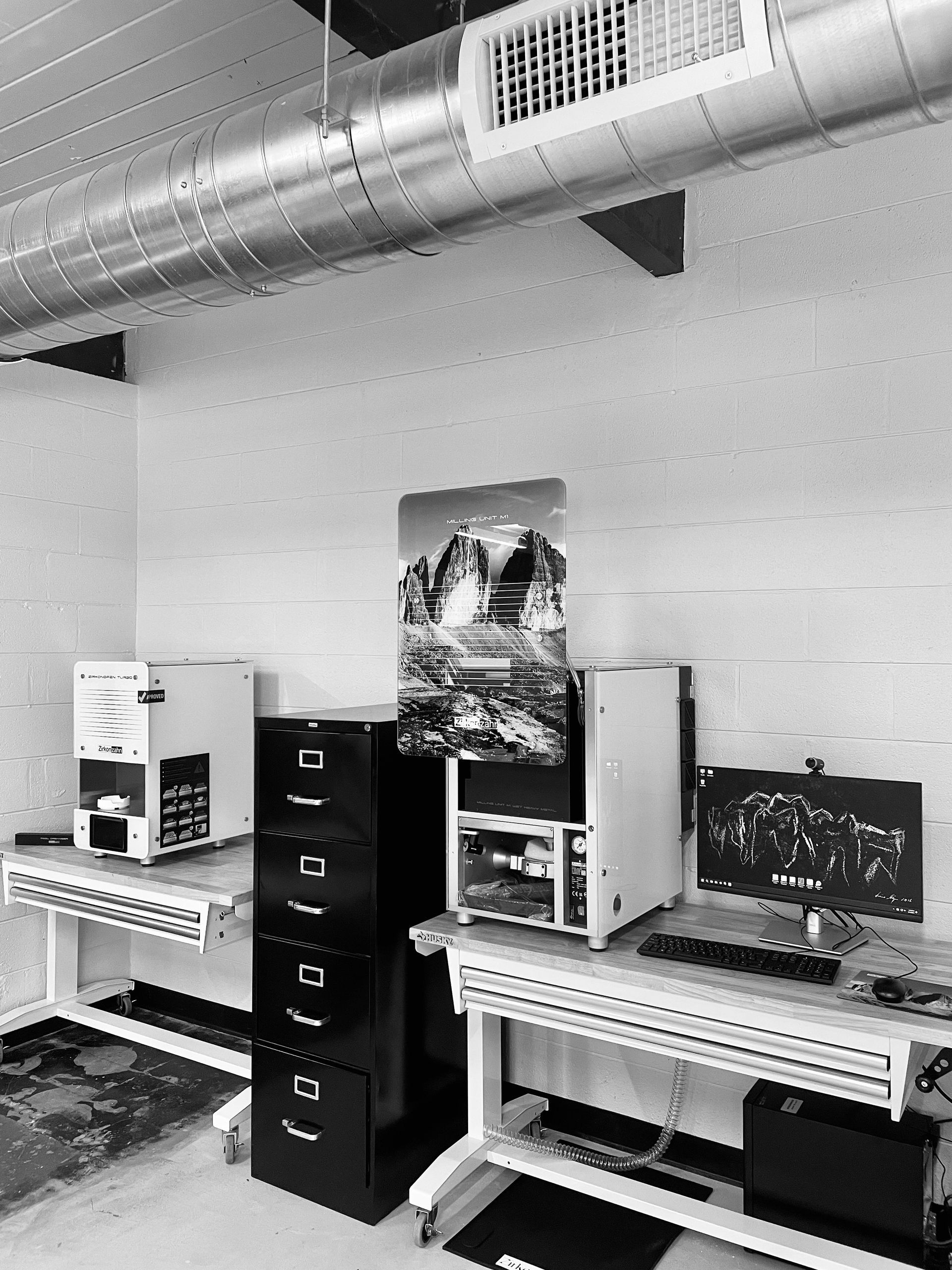 Laboratory workspace with equipment, black file cabinet, and a cityscape poster.