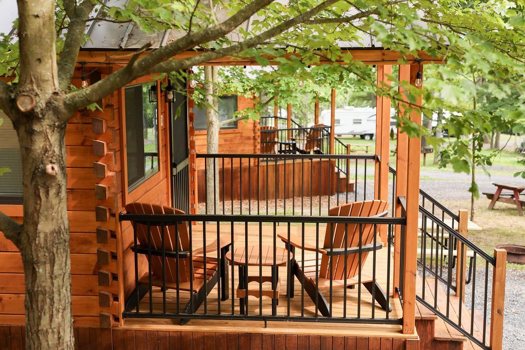A wooden cabin with a porch with chairs and a table.
