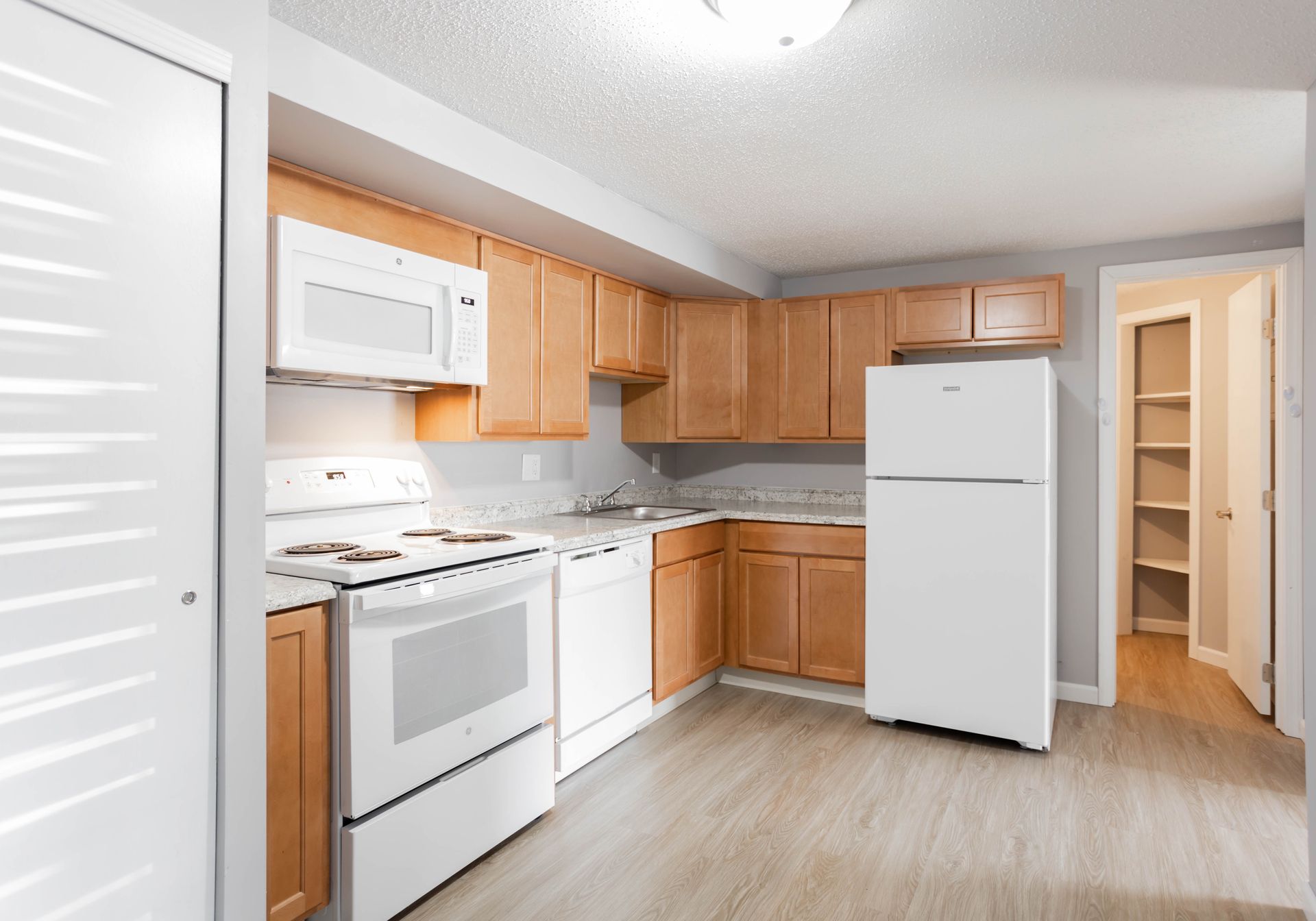 An empty living room with a sliding glass door and blinds.