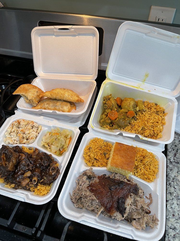 Four takeout meals in white foam containers on a table, with fried rice, chicken, and saucy meat dishes.