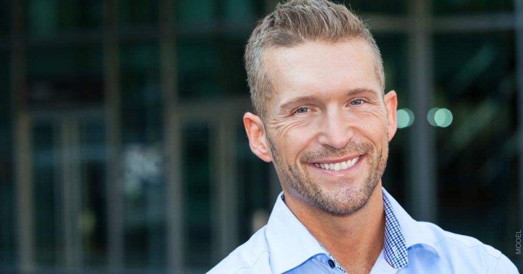 Smiling man in light blue shirt, outside, looking at the viewer.