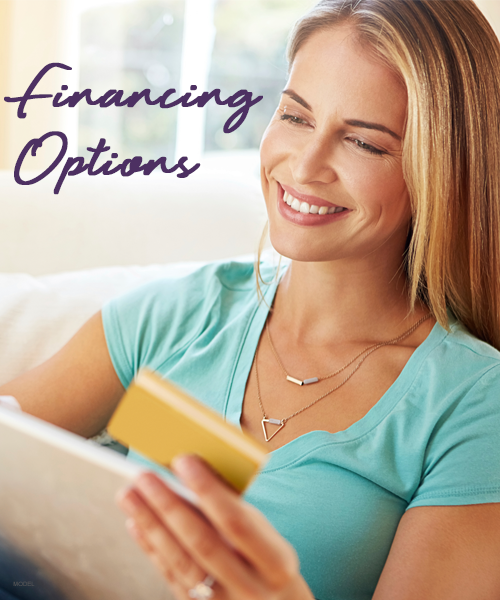 Woman smiling, looking at a tablet, holding a credit card. Text: Financing Options.