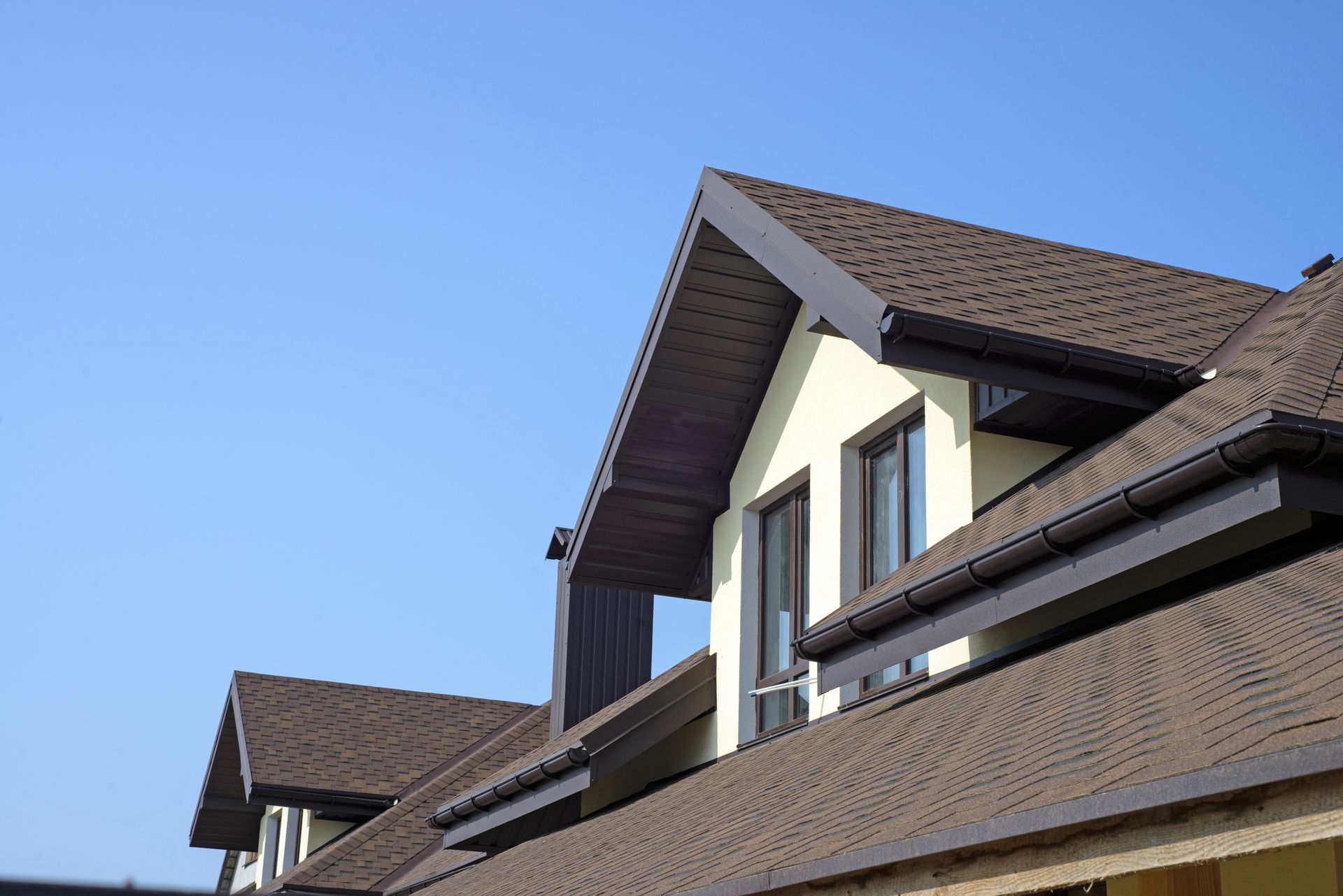 Close-up of brown-roofed house gables against a clear blue sky