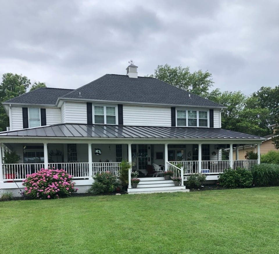 Red ladder leaning against a beige house under construction against a clear blue sky.