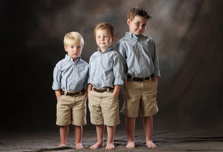 three young boys standing next to each other with their hands in their pockets