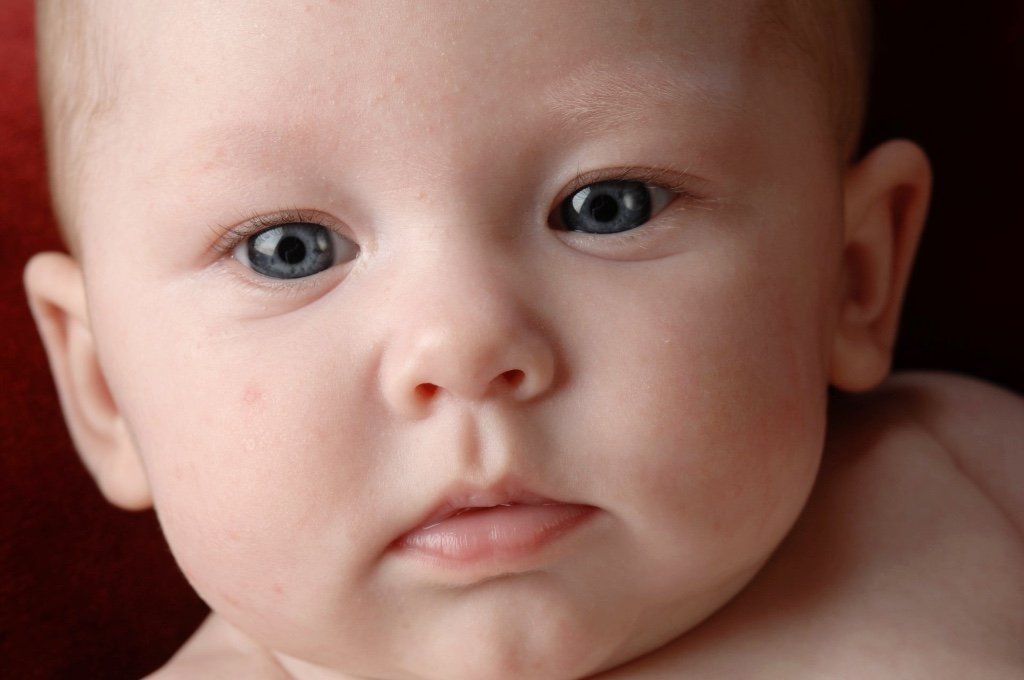 a close up of a baby 's face with blue eyes