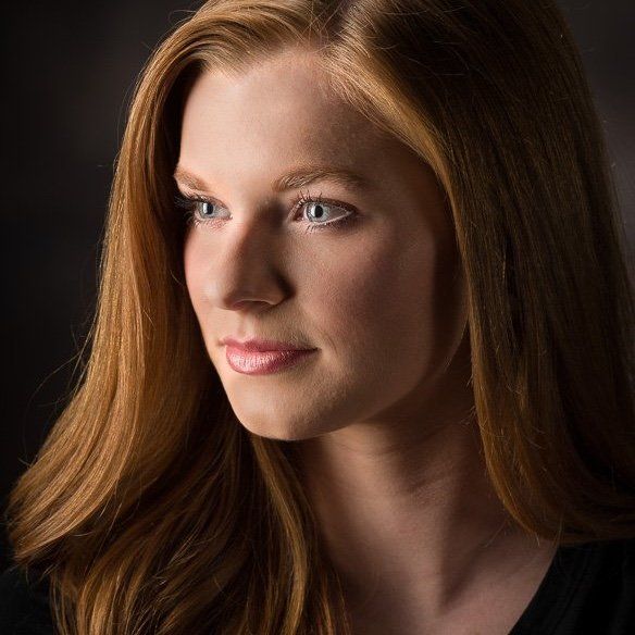 a woman with long red hair is wearing a black shirt