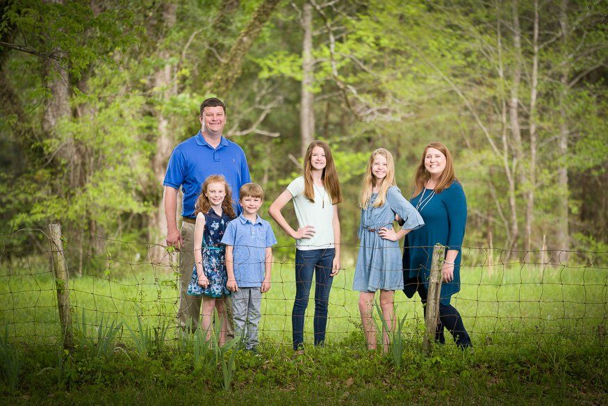 a family poses for a picture in front of a barbed wire fence
