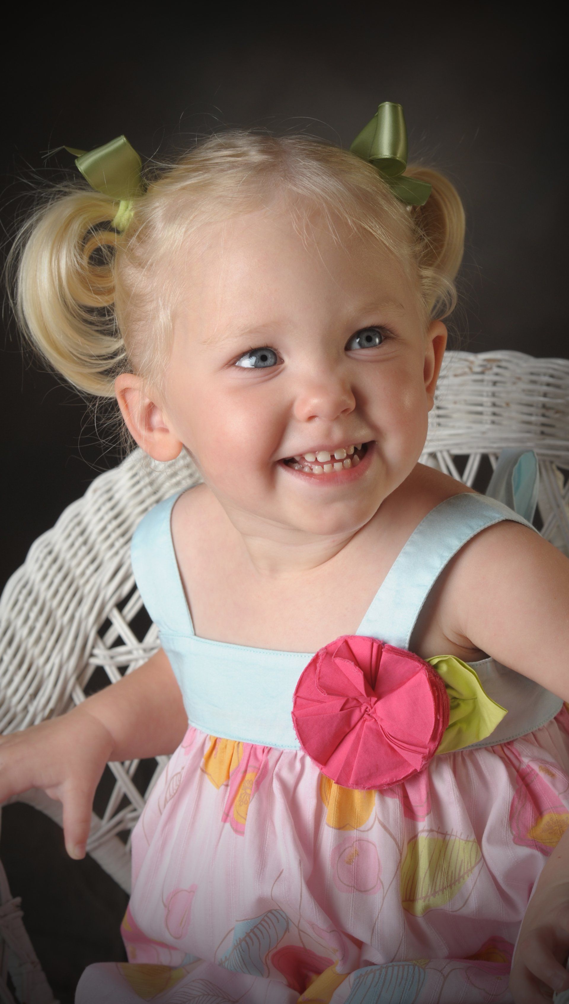a little girl wearing a pink dress with a pink flower on the front