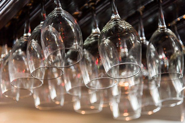a bunch of wine glasses are hanging from the ceiling .