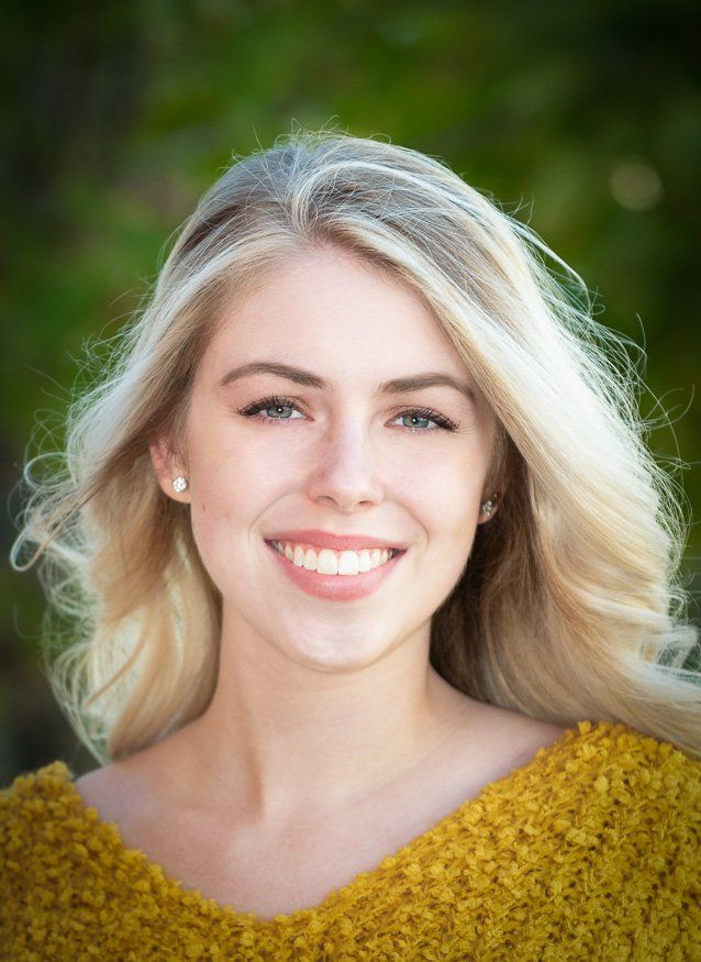 a woman wearing a yellow sweater smiles for the camera