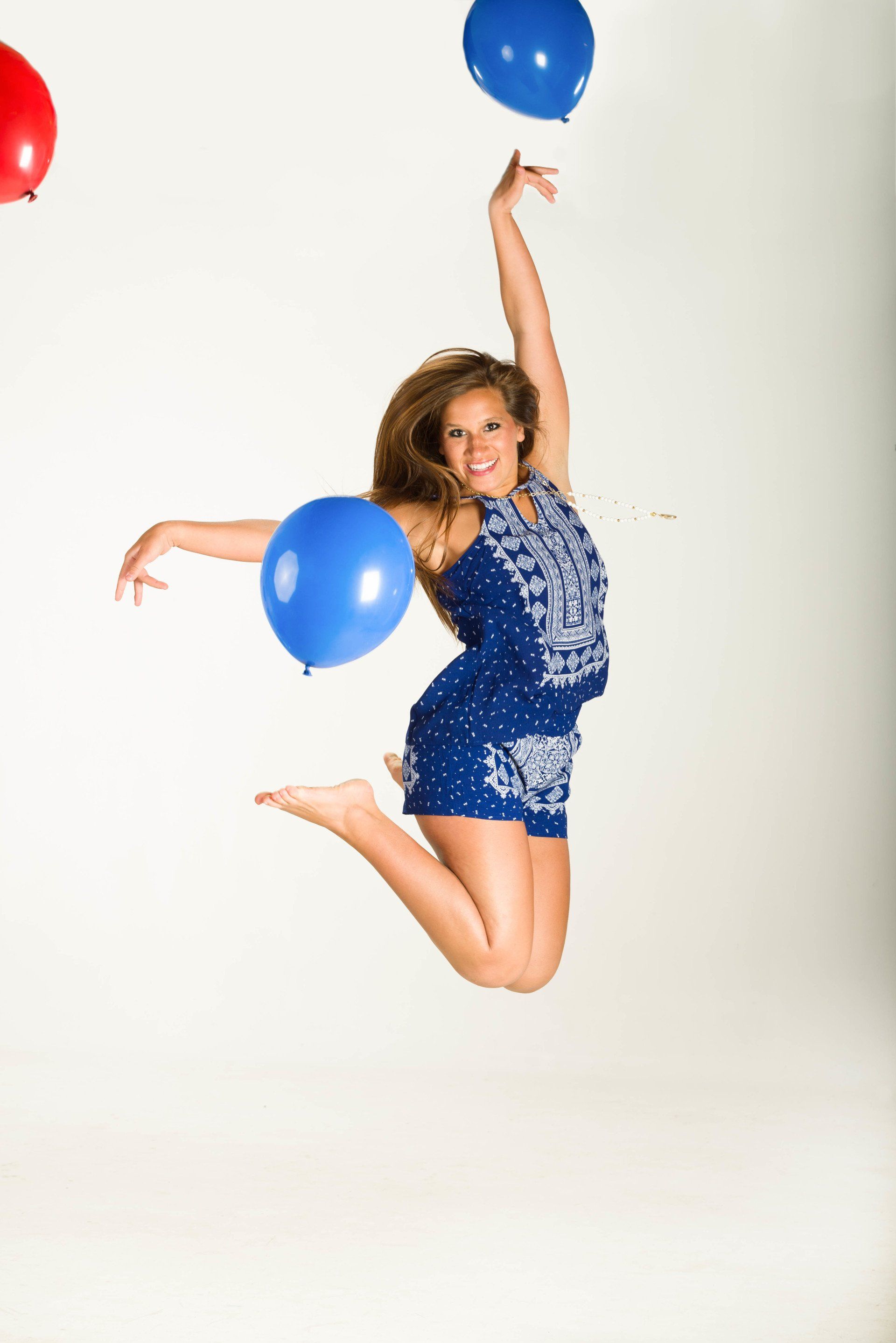 a woman in a blue outfit is jumping in the air with balloons