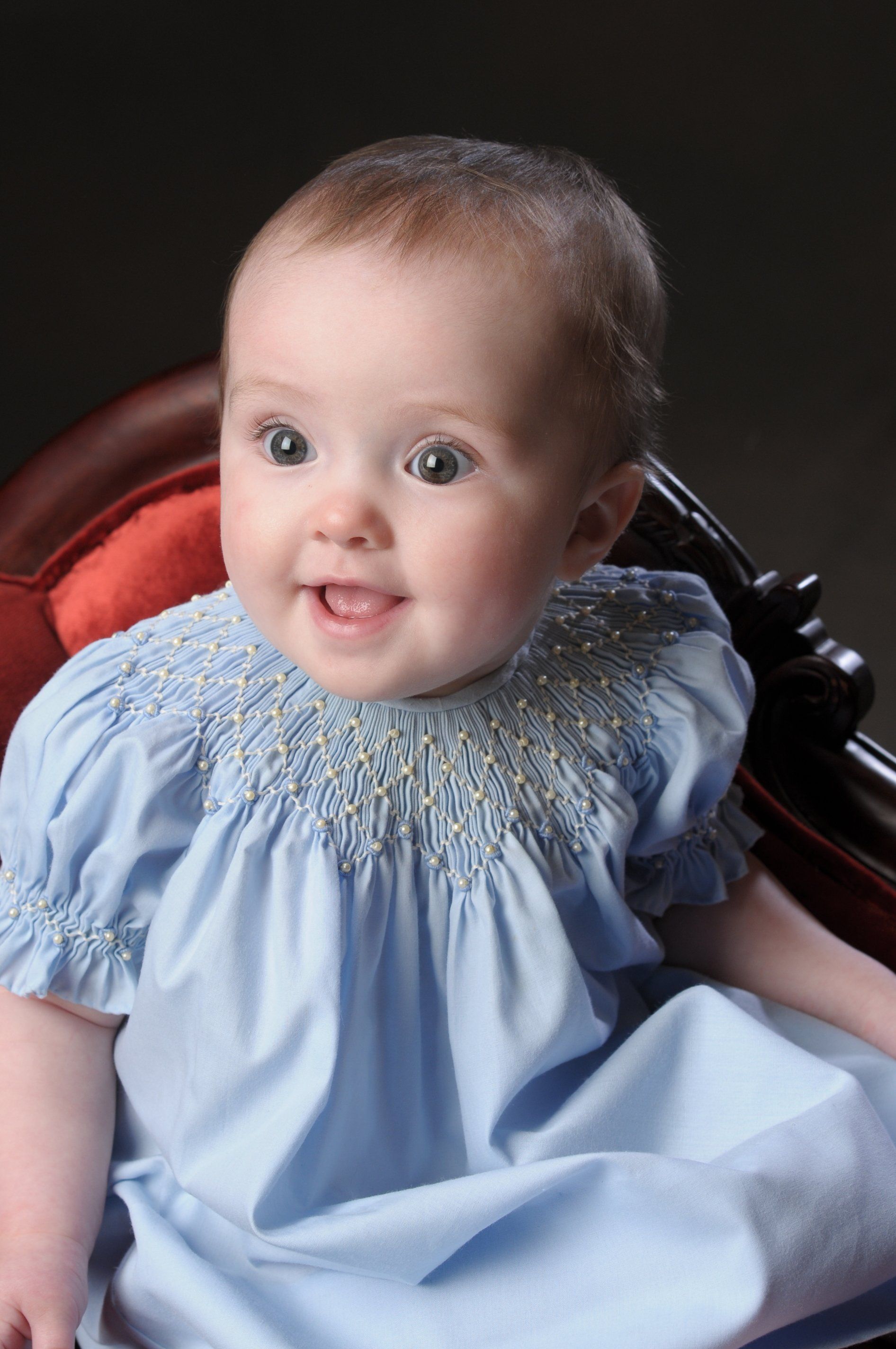 a baby in a blue dress is smiling for the camera