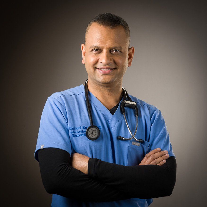 a man in a blue scrub with a stethoscope around his neck is smiling