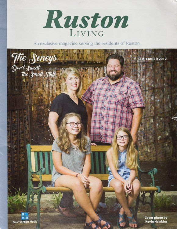 A family is sitting on a bench on the cover of a ruston living magazine.