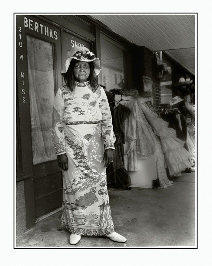 a woman stands in front of a store called berthas