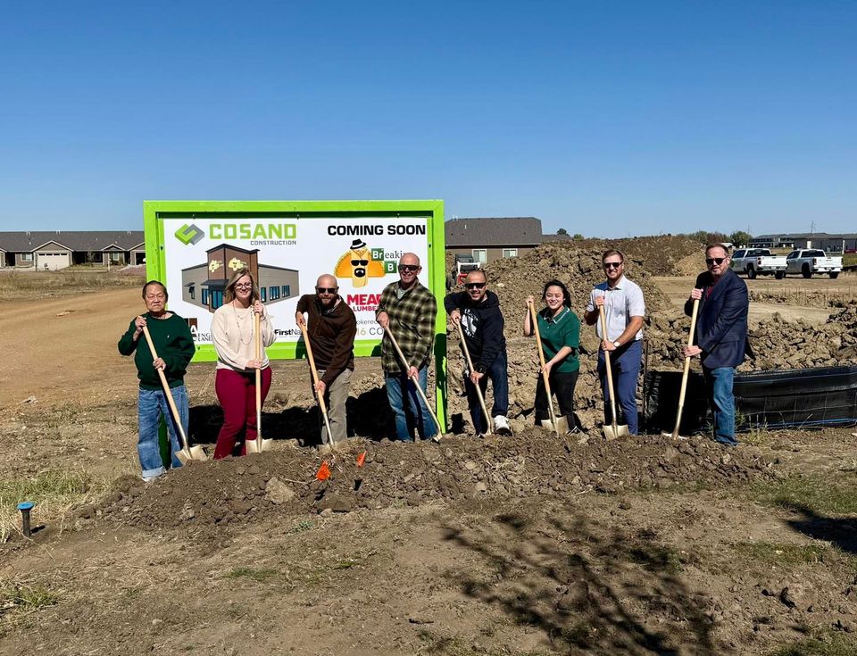Group of people with shovels at a ground breaking event. Green sign reads 